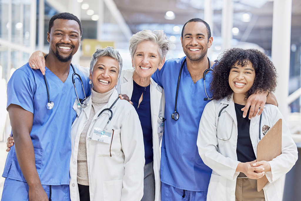 Happy Portrait, Group And Doctors For Healthcare Service, Leadership And Teamwork In Hospital Diversity. Professional Medical Woman, Mentor And Internship Nurses In Clinic Management, Hug And Support